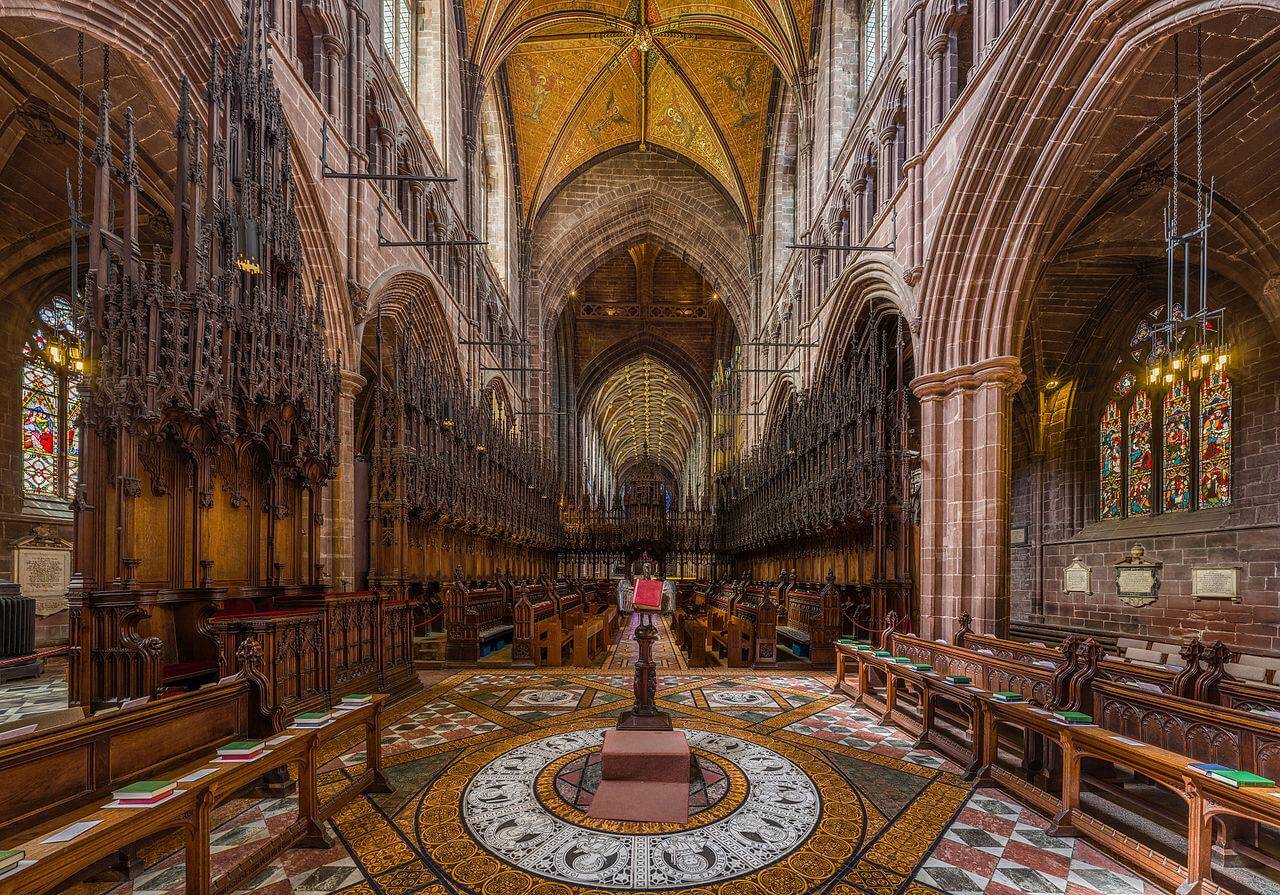 The inside of a cathedral with wooden benches and a clock.