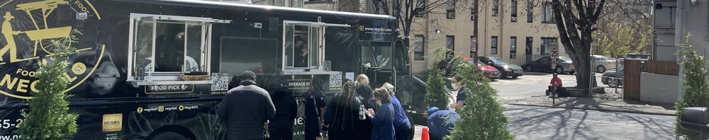 A black food truck is parked on a street.