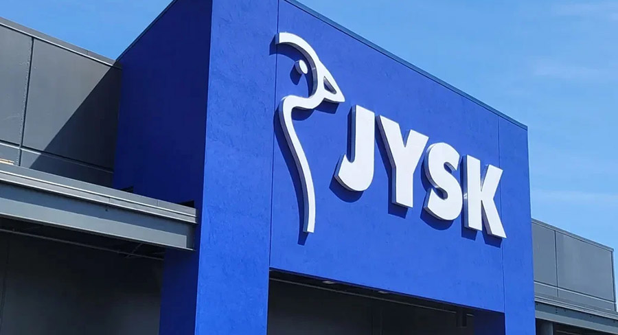 The exterior of a blue JYSK store with a company logo featuring a bird silhouette.